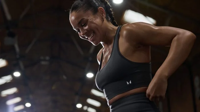 A young woman smiling during an indoor workout.